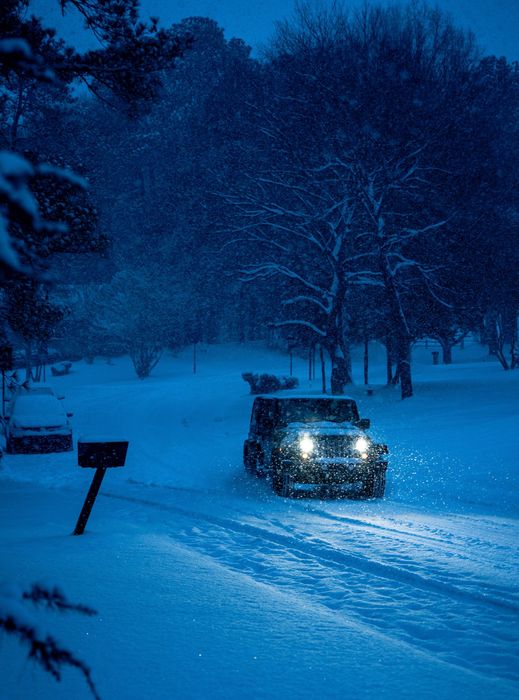 Jeep driving through blizzard at night