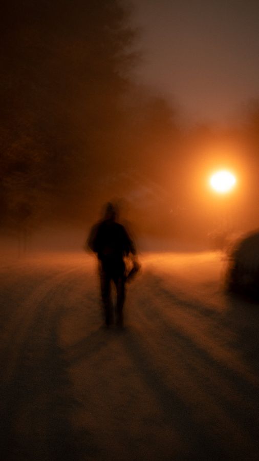Figure walking in orange snowstorm at night