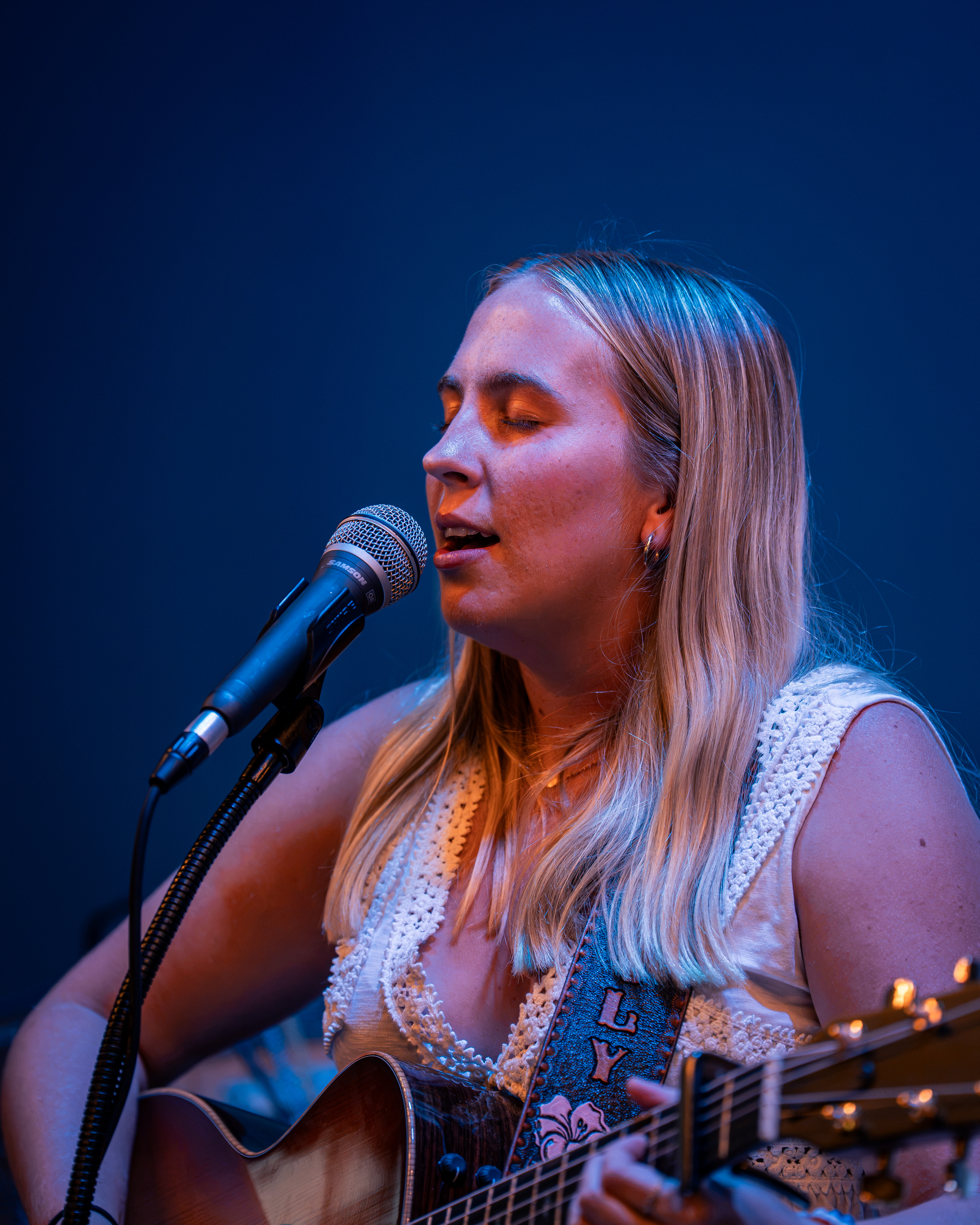 Singer performing at open mic under blue stage light