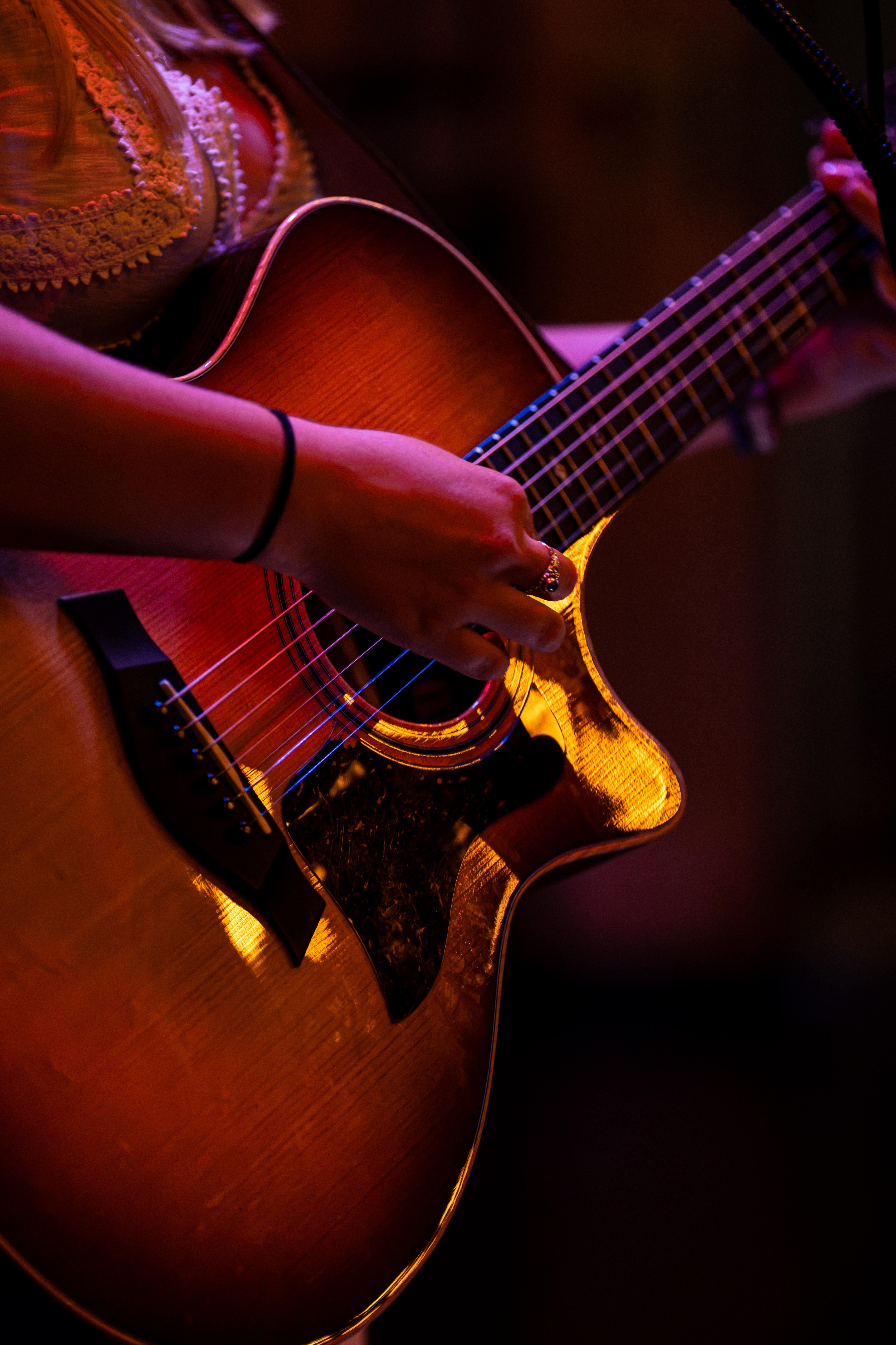 Close up of guitar being played under warm stage light
